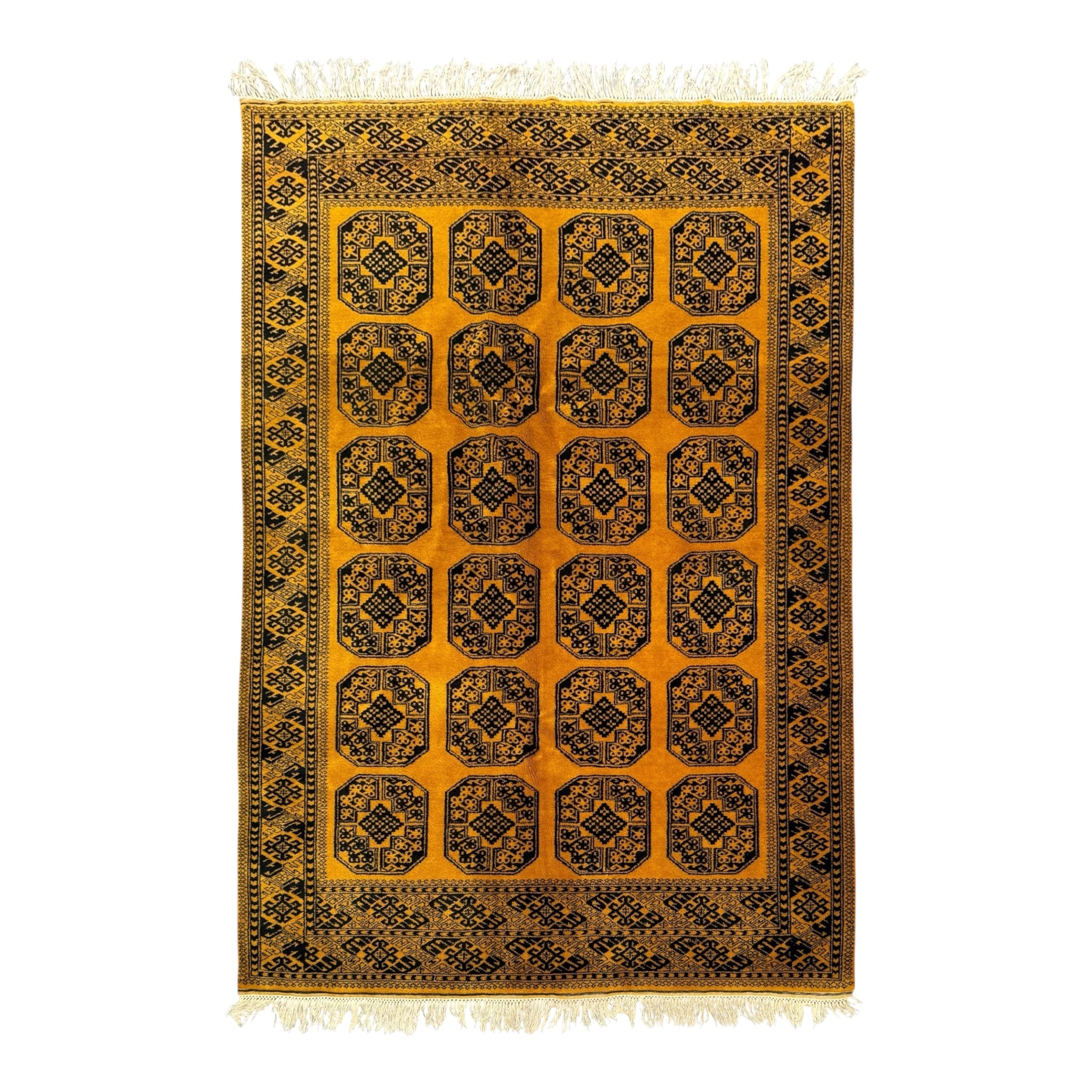 A rectangular area rug with a mustard yellow field, featuring a grid of black and brown geometric medallion motifs and a detailed border, finished with cream-colored fringe on the top and bottom.