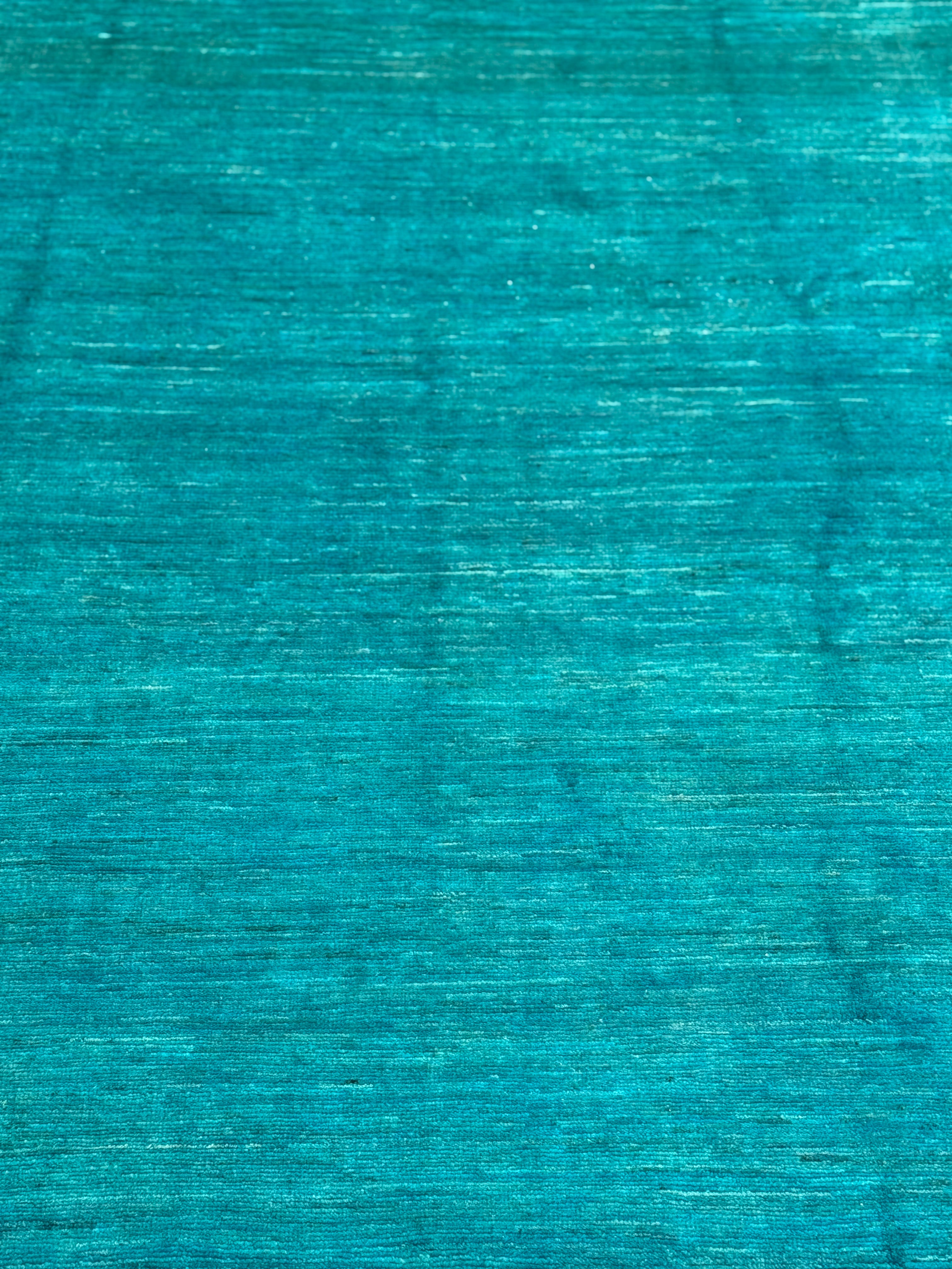 A close-up of a textured turquoise blue Handmade Wool rug with a fine, heathered weave.